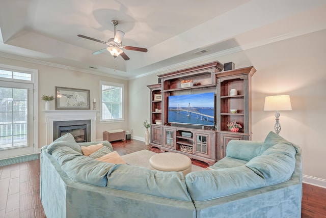 living room featuring crown molding, ceiling fan, wood-type flooring, and a raised ceiling