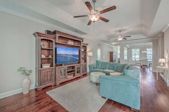 living room with ornamental molding, dark wood-type flooring, ceiling fan, and a tray ceiling