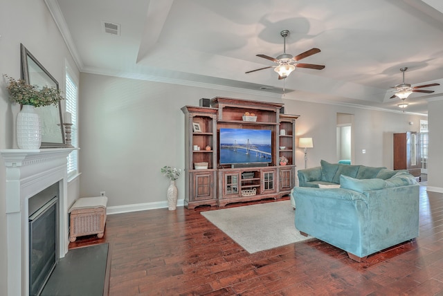 living room featuring dark hardwood / wood-style flooring, ornamental molding, a raised ceiling, and ceiling fan