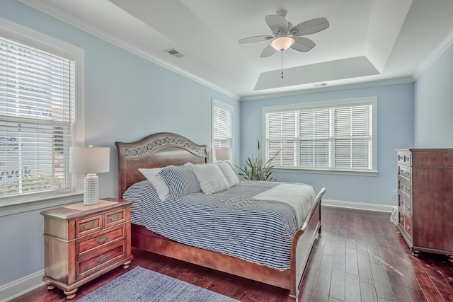 bedroom with crown molding, dark wood-type flooring, a raised ceiling, and ceiling fan