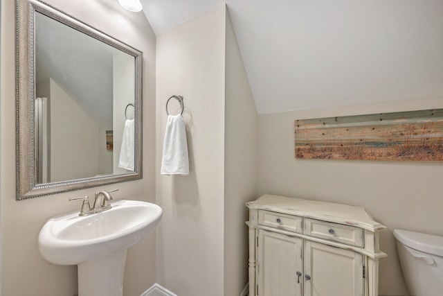 bathroom featuring sink, vaulted ceiling, and toilet