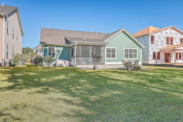 rear view of house with a sunroom, a patio area, and a lawn