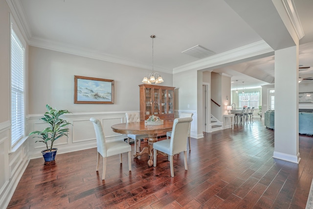 dining room featuring dark wood-type flooring, ornamental molding, and a chandelier