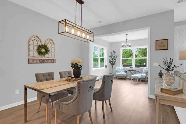 dining space with an inviting chandelier, baseboards, wood finished floors, and visible vents