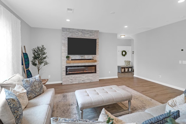 living area with baseboards, a fireplace, wood finished floors, and visible vents