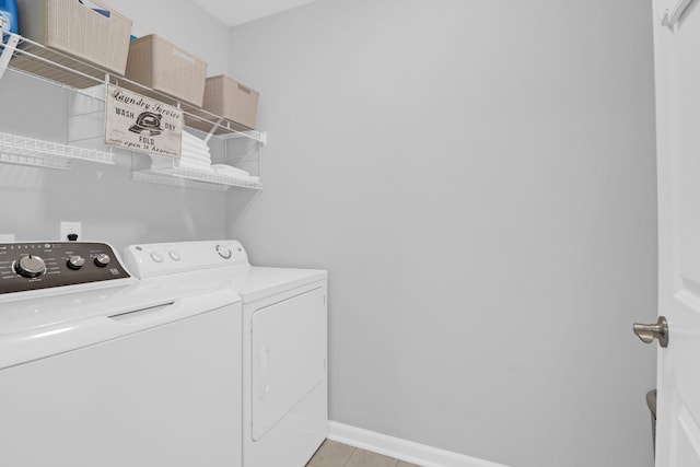washroom with laundry area, baseboards, independent washer and dryer, and light tile patterned flooring
