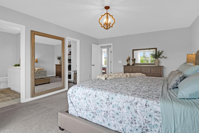 carpeted bedroom with connected bathroom, a notable chandelier, a walk in closet, and a closet