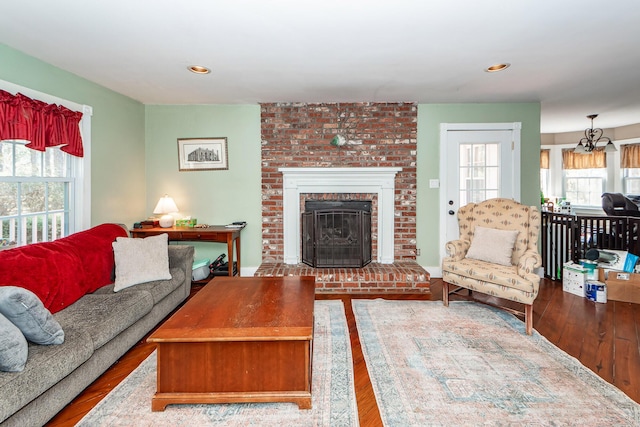 living area featuring recessed lighting, a brick fireplace, and wood finished floors