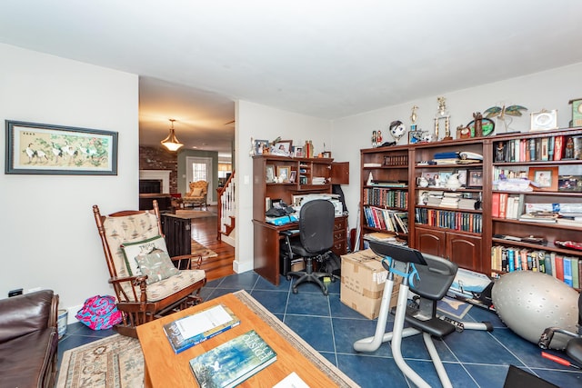 office featuring dark tile patterned floors, a fireplace, and baseboards