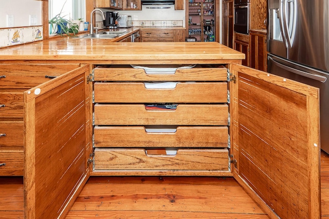 kitchen featuring wood finished floors, appliances with stainless steel finishes, and a sink