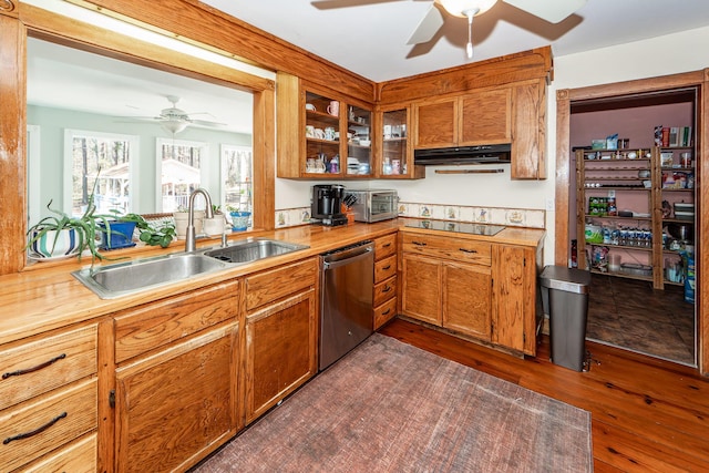 kitchen featuring glass insert cabinets, brown cabinets, stainless steel dishwasher, under cabinet range hood, and a sink