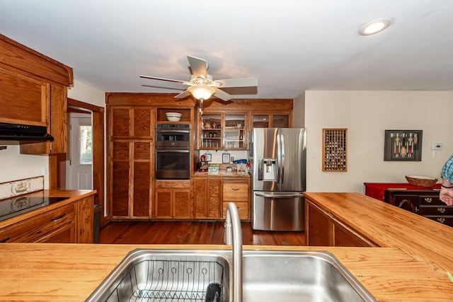 kitchen with dark wood-style floors, wood counters, stainless steel appliances, ventilation hood, and a sink