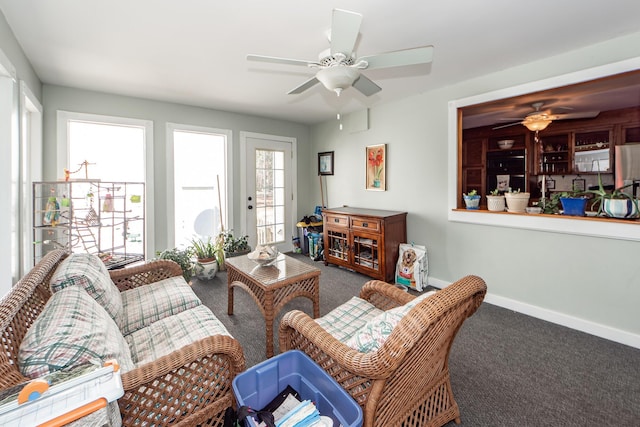 carpeted living area featuring ceiling fan and baseboards