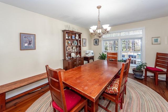 dining space with wood finished floors and a notable chandelier