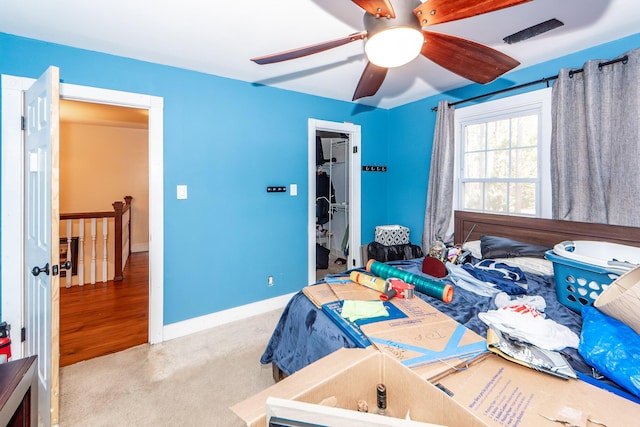 bedroom with baseboards, a ceiling fan, a walk in closet, carpet flooring, and a closet