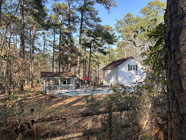 rear view of house featuring an outbuilding, an outdoor pool, and a storage structure