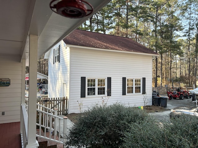 view of property exterior with roof with shingles and fence