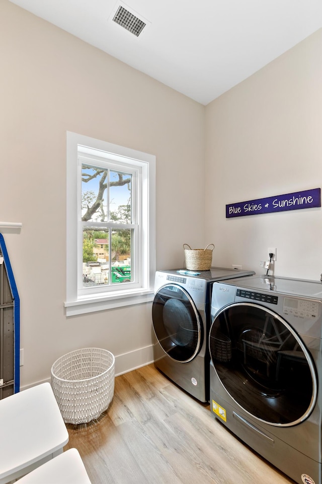 washroom featuring visible vents, wood finished floors, washing machine and dryer, and laundry area