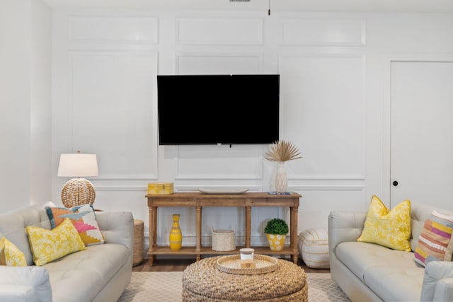 living area with a decorative wall and wood finished floors