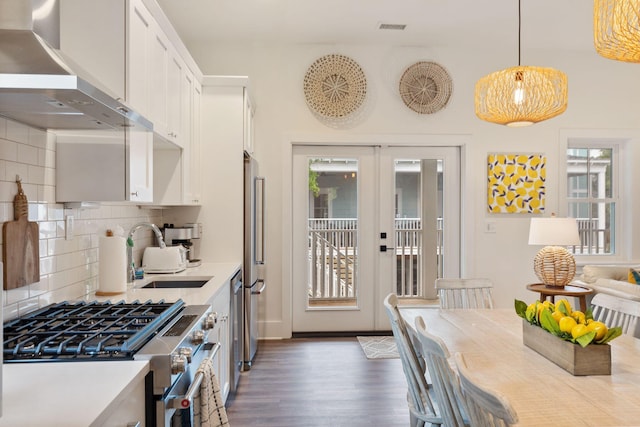 kitchen featuring visible vents, wall chimney range hood, stainless steel appliances, dark wood-style floors, and white cabinetry