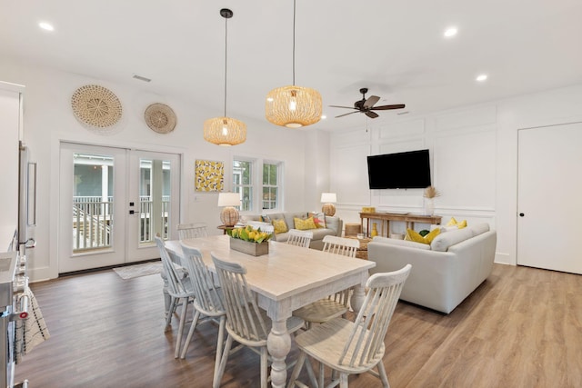 dining space with a decorative wall, recessed lighting, french doors, and light wood finished floors