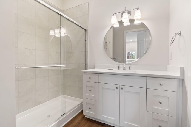 full bathroom with vanity, a shower stall, and wood finished floors