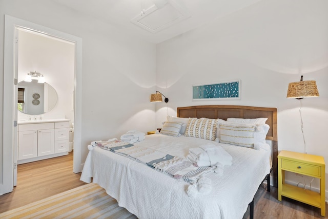 bedroom with connected bathroom, attic access, light wood-type flooring, and a sink