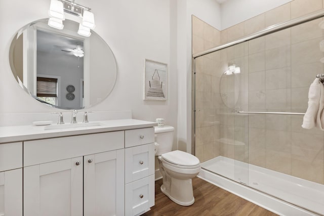 full bath featuring vanity, a ceiling fan, wood finished floors, a stall shower, and toilet