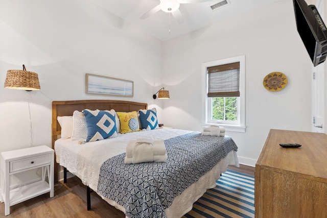 bedroom with ceiling fan, wood finished floors, visible vents, and baseboards