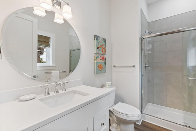 full bath with vanity, toilet, wood finished floors, and a tile shower