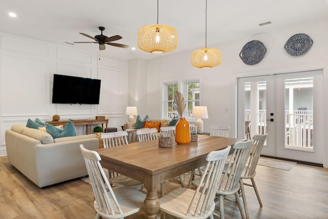 dining room with visible vents, light wood-type flooring, recessed lighting, french doors, and a decorative wall