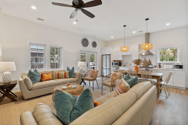 living area with recessed lighting, visible vents, light wood-style floors, and french doors