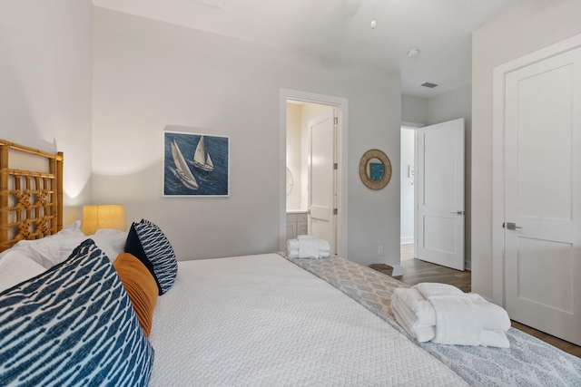 bedroom featuring visible vents, ensuite bath, and wood finished floors