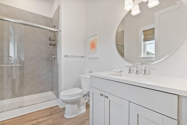 full bath with vanity, toilet, wood finished floors, and a stall shower