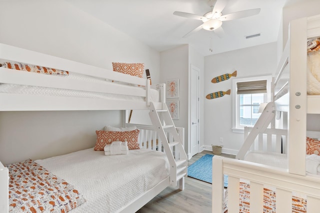 bedroom with visible vents, a ceiling fan, baseboards, and wood finished floors