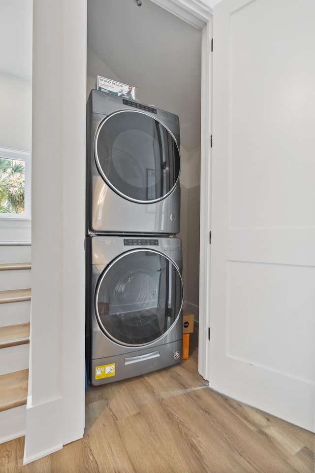 washroom with laundry area, stacked washer / dryer, and wood finished floors