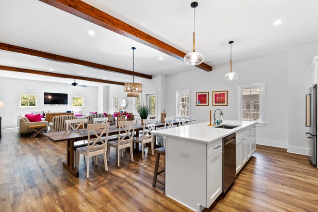 kitchen with white cabinets, beamed ceiling, appliances with stainless steel finishes, and a sink