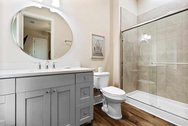 bathroom with visible vents, toilet, wood finished floors, a shower stall, and vanity