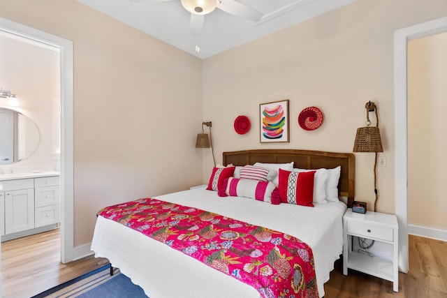 bedroom with a ceiling fan, wood finished floors, baseboards, and connected bathroom