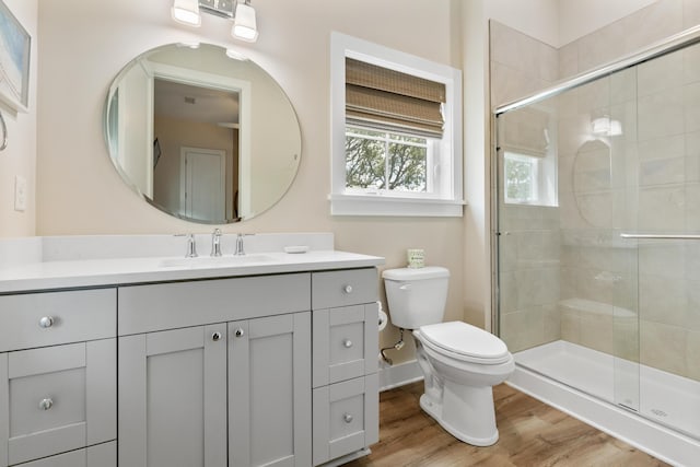 bathroom with a stall shower, toilet, wood finished floors, and vanity