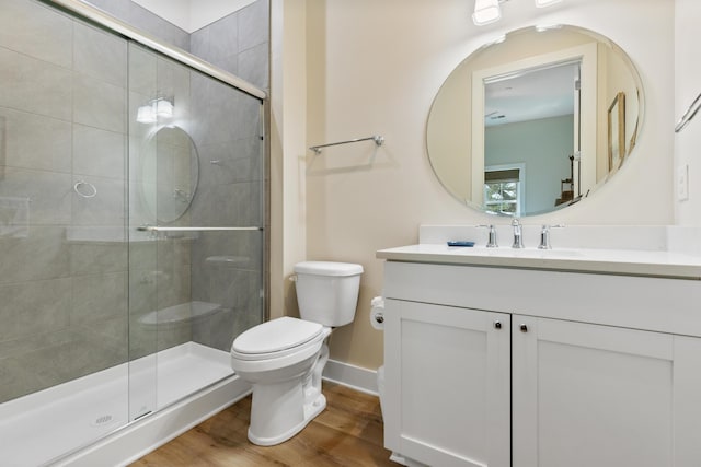 bathroom with vanity, wood finished floors, baseboards, a stall shower, and toilet