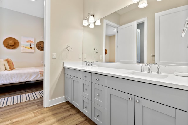 full bathroom with double vanity, wood finished floors, baseboards, and a sink