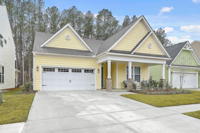 craftsman-style house featuring a front yard, concrete driveway, a garage, and a shingled roof