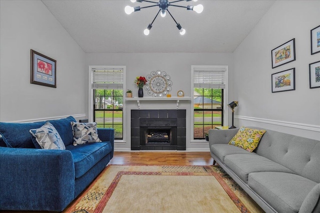 58 Indigo Ln, Goose Creek, SC 29445 - living room with wood finished floors, healthy amount of natural light, vaulted ceiling, a tiled fireplace, and a chandelier