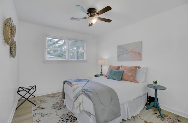 bedroom with ceiling fan, wood finished floors, and baseboards