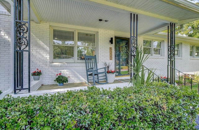 property entrance featuring covered porch and brick siding