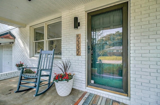 property entrance featuring a porch and brick siding