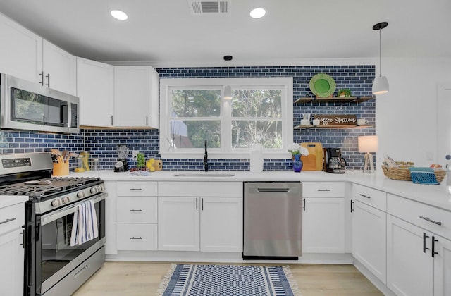 kitchen featuring visible vents, stainless steel appliances, white cabinetry, open shelves, and a sink