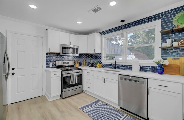 kitchen featuring visible vents, white cabinets, light wood-style flooring, appliances with stainless steel finishes, and a sink