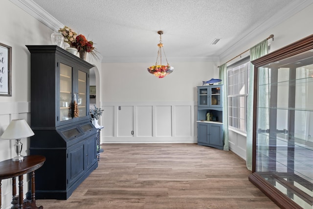 6242 Fieldstone Cir, Charleston, SC 29414 - unfurnished dining area with a decorative wall, ornamental molding, a textured ceiling, light wood-style floors, and a wainscoted wall